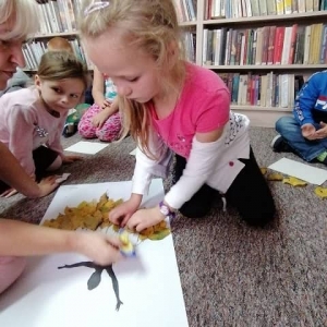 Dzieci przyklejające liście do obrazu Pani Jesieni