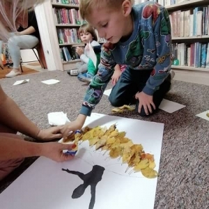 Dzieci przyklejające liście do obrazu Pani Jesieni
