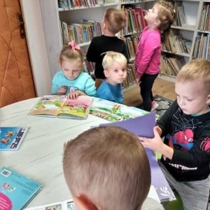 Dzieci przeglądające książeczki i szukające książek na półce
