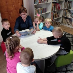 Dzieci słuchające jak Pani Bibliotekarka czyta książkę