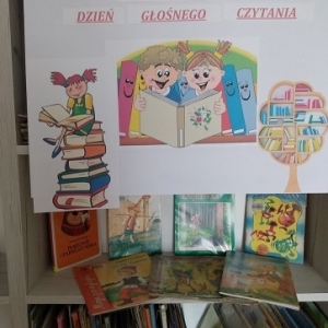 Wystwka książek dziecięcych oraz plakat z hasłem "Ogólnopolski Dzień Głośnego Czytania Dzieciom"