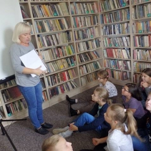 Bibliotekarka i dzieci biorące udział w lekcji bibliotecznej