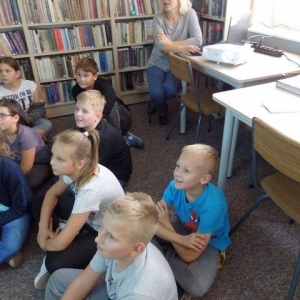 Bibliotekarka i czytelnicy oglądający prezentację multimedialną