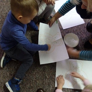 Dzieci wykonują pracę plastyczną-  z kaszy, ryżu i sztucznego śniegu tworzą obrazek misia