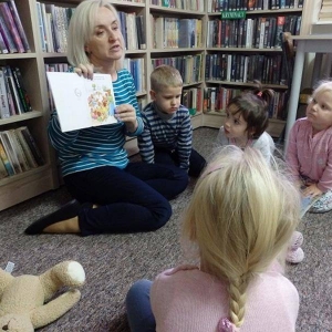 Dzieci słuchają bajki czytanej przez panią bibliotekarkę